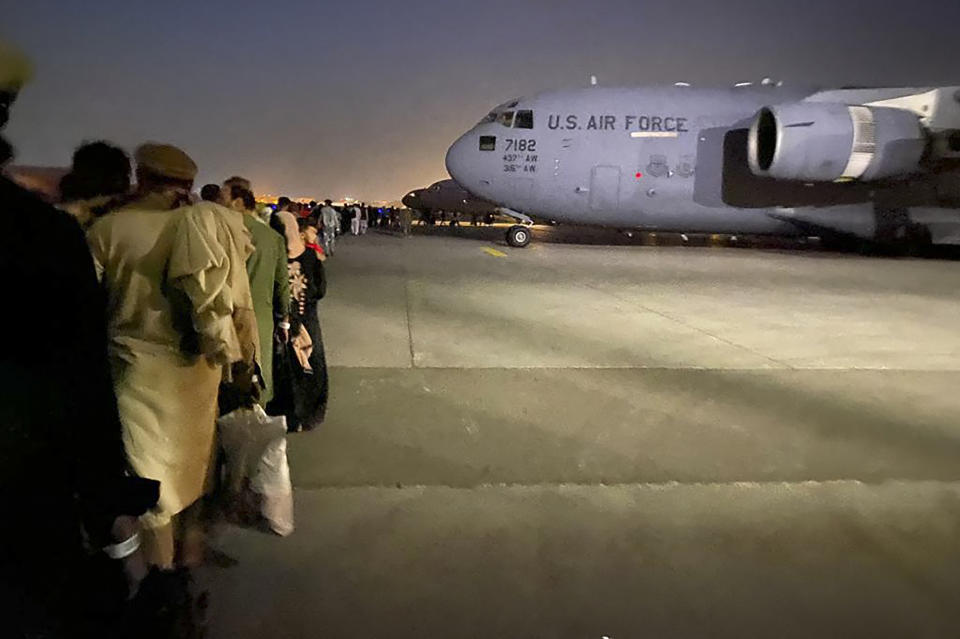 Afghan people queue up and board a U S military aircraft to leave Afghanistan, at the military airport in Kabul on August 19, 2021. (Shakib Rahmani/AFP via Getty Images)