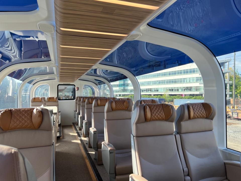 Tan seats and blue ceiling with a glass roof area on a train