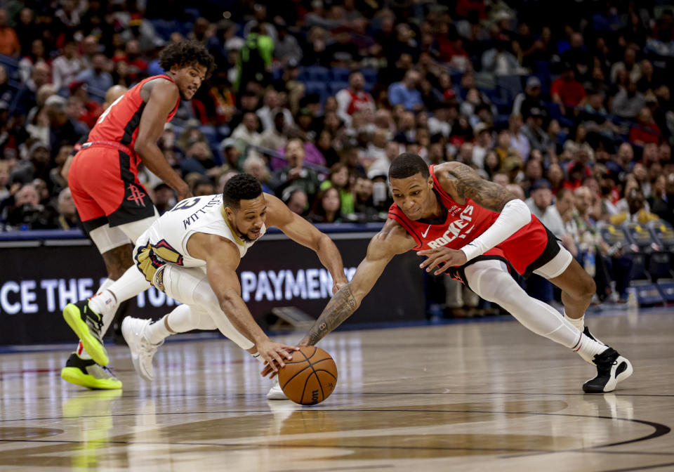 Houston Rockets forward Jabari Smith Jr., right, and New Orleans Pelicans guard CJ McCollum (3) scramble for the ball during the first half of an NBA basketball game in New Orleans, Thursday, Feb. 22, 2024. (AP Photo/Derick Hingle)