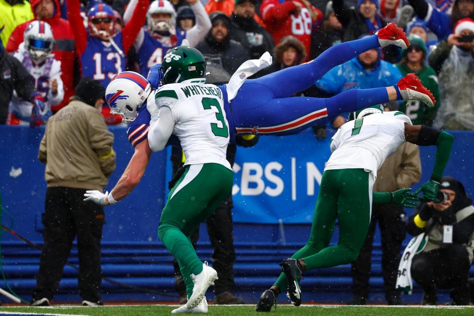 Buffalo Bills tight end Dawson Knox, behind top, jumps into the end zone past New York Jets safety Jordan Whitehead (3) and cornerback Sauce Gardner (1) for a touchdown during the first half of an NFL football game, Sunday, Dec. 11, 2022, in Orchard Park, N.Y. (AP Photo/Jeffrey T. Barnes)