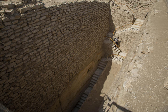 A journalist walks down stairs towards the southern cemetery of King Djoser, to film it after its restoration, near the famed Step Pyramid, in Saqqara, south of Cairo, Egypt, Tuesday, Sept. 14, 2021. (AP Photo/Nariman El-Mofty)