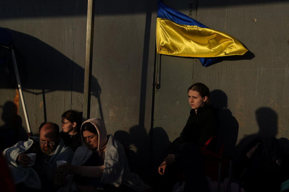 FILE - Ukrainian refugees wait near the U.S. border in Tijuana, Mexico, April 4, 2022. A month after Russia invaded Ukraine, refugees started showing up to the U.S.-Mexico border. Roughly 1,000 Ukrainians a day flew to Tijuana on tourist visas, desperate to get into the country. The volume was overwhelming the nation’s busiest border crossing in San Diego. Just over the border in Tijuana Mexico, thousands of Ukrainians slept in a municipal gym hoping to for a chance to get across. (AP Photo/Gregory Bull, File)