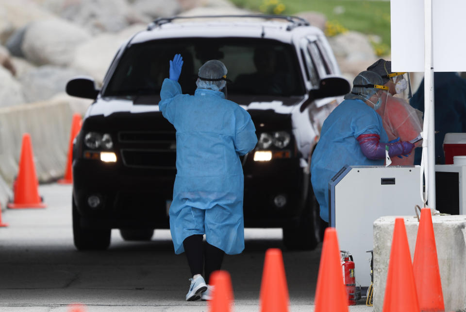 In this Friday, May 1, 2020, photo, a medical worker directs a local resident at a drive-thru COVID-19 testing site in Waterloo, Iowa. Local officials blame Tyson for endangering not only its workers and their relatives during the pandemic but everyone else who leaves home to work or get groceries. They are furious with the state and federal governments for failing to intervene — and for pushing hard to reopen the plant days after public pressure helped shut it down. (AP Photo/Charlie Neibergall)