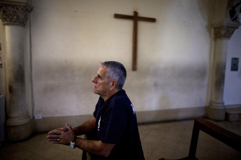 In this May 11, 2013 photo, a man prays to La Virgen Desatanudos at the San Jose del Talar parish, in Buenos Aires, Argentina. With an Argentine on the throne of St. Peter, the South American country's capital city has launched a series of guided tours that include the San Jose del Talar parish, where visitors can pray at the sanctuary that features a painting of the Virgin untying knots and passing them to angels. Pope Francis had the painting brought from Germany in the 1980s, and ever since, attendance at the church has soared. (AP Photo/Natacha Pisarenko)