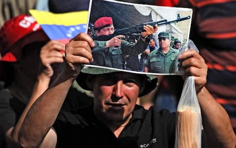 A Venezuelan government supporter holds a picture of late president Hugo Chavez during a rally in Caracas on May 20, 2019 - Credit: AFP