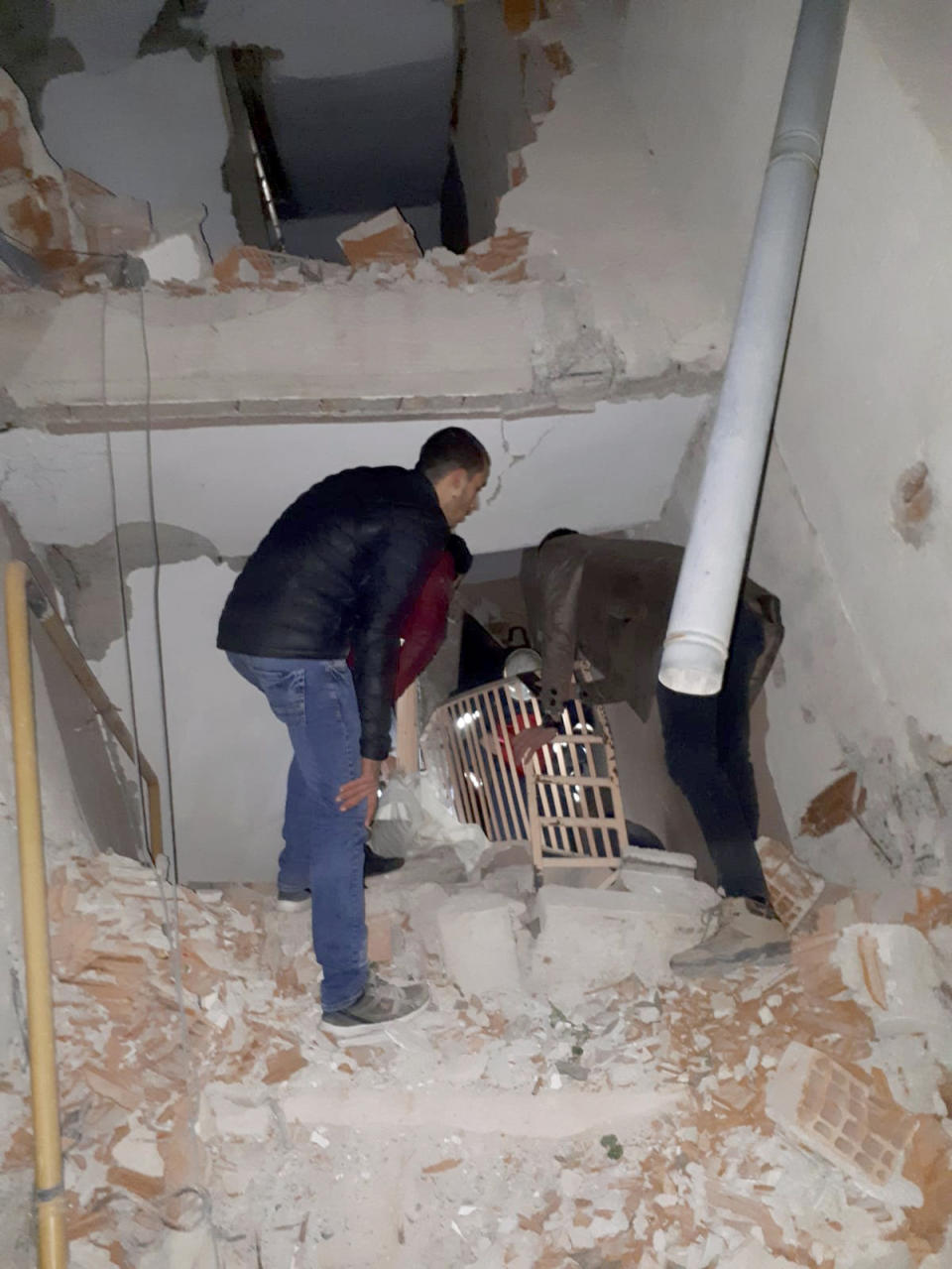 Two men check inside a badly damaged building after a 6.8 earthquake struck Elazig city centre in the eastern Turkey, Friday, Jan. 24, 2020. An earthquake with a preliminary magnitude of 6.8 rocked eastern Turkey on Friday, causing some buildings to collapse and killing at least four people, Turkish officials said. (DHA via AP)