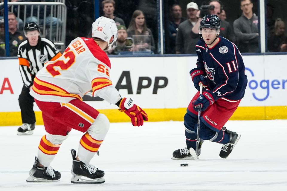 Oct 20, 2023; Columbus, Ohio, USA; Columbus Blue Jackets center Adam Fantilli (11) skates with the puck toward Calgary Flames defenseman MacKenzie Weegar (52) during the first period of the NHL hockey game at Nationwide Arena.