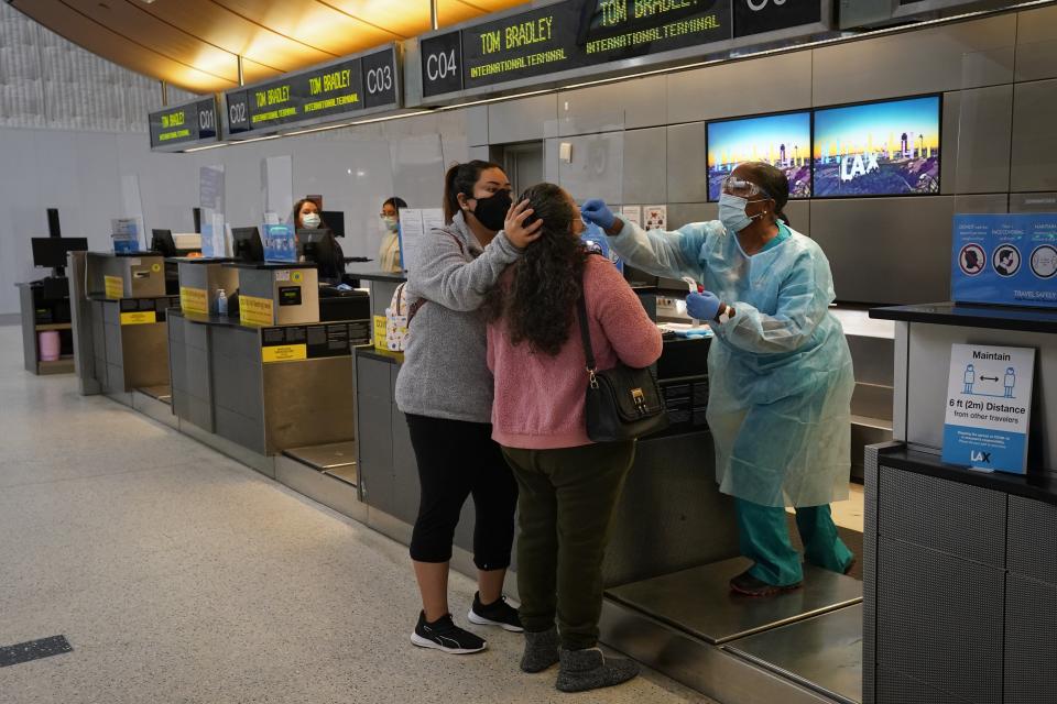 FILE - Licensed vocational nurse Caren Williams, right, collects a nasal swab sample from a traveler at a COVID-19 testing site at the Los Angeles International Airport in Los Angeles, on Nov. 23, 2020. The Biden administration is lifting its requirement that international air travelers to the U.S. take a COVID-19 test within a day before boarding their flights, easing one of the last remaining government mandates meant to contain the spread of the coronavirus. (AP Photo/Jae C. Hong, File)