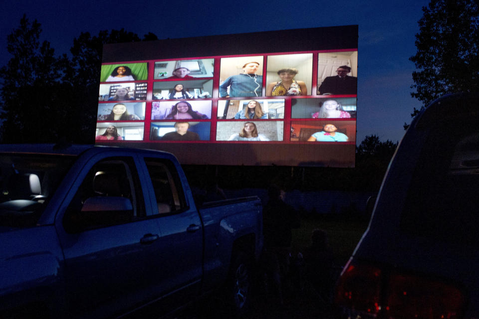 An outdoor movie screen showcases 15 choir students singing the class song, One Republic's "I Lived," during a 90-minute graduation film as about 650 Grand Blanc High School seniors attend a commencement ceremony Thursday, June 4, 2020, at a drive-in movie theater in Mundy Township, Mich. The school district switched to the location for the commencement ceremony to provide a safe space for social distancing due to the COVID-19 pandemic. (Jake May/The Flint Journal via AP)