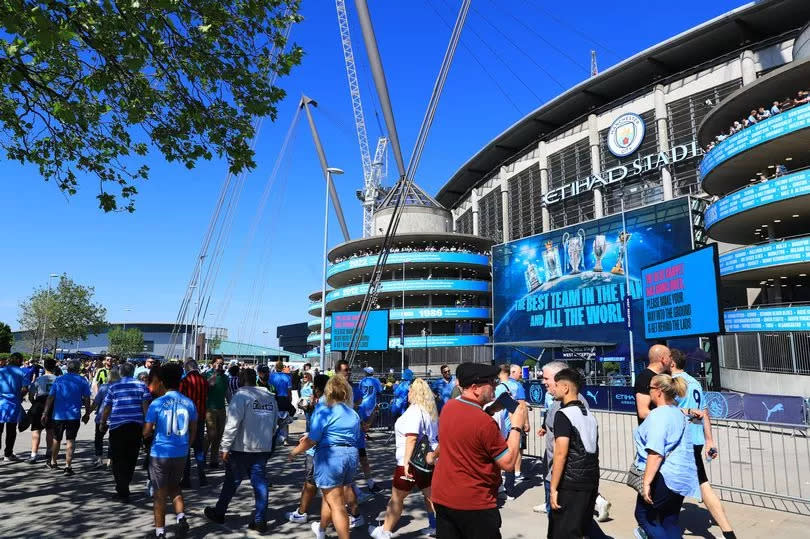 Fans walk past the Etihad stadium