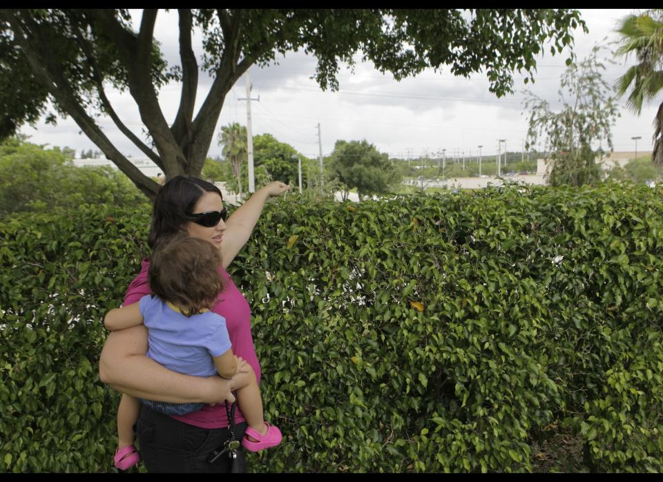 In this photo taken Tuesday, July 26, 2011, Ryann Greenberg, left, stands with her daughter Ava, 2, in their back yard as she points to land in the distance where a proposed detention center would be built in Pembroke Pines, Fla. Town leaders in nearby Southwest Ranches have plans to build a 1,500-bed detention center facility for U.S. Immigration and Customs Enforcement. A growing group of residents from Southwest Ranches and neighboring cities are seeking to halt the effort. (AP Photo/Lynne Sladky)