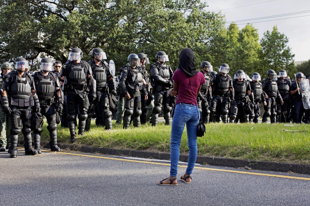 A protester watches as police in riot gear clear the street of protesters in front of the Baton Rouge Police Department headquarters in Baton Rouge, La., Saturday, July 9, 2016. (AP Photo/Max Becherer)