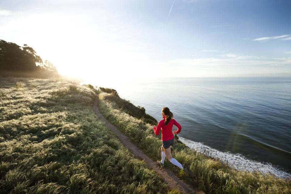 Woman running on a cliff alongside the ocean