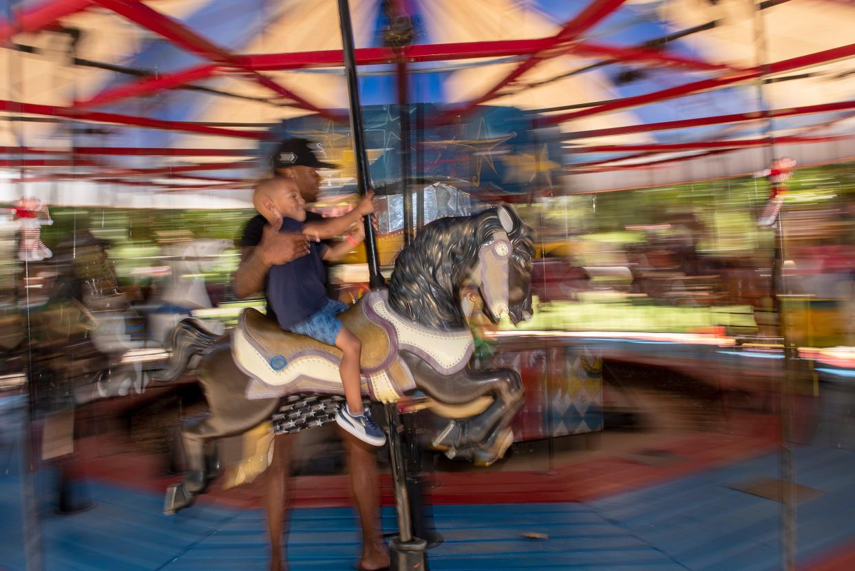 Bobby Reese and his daughter Corteney, 3, both of Stockton, ride on the carousel at the Christmas in July event at Pixie Woods on July 23.