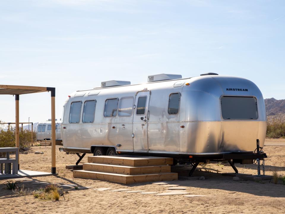 An Airstream trailer next to a shaded seating area.