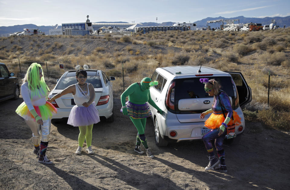 From left, Alex Clark, Carolyn Milner, Audrie Clark and Lucinda Clark dance near their car outside of the Storm Area 51 Basecamp event Friday, Sept. 20, 2019, in Hiko, Nev. The event was inspired by the "Storm Area 51" internet hoax. (AP Photo/John Locher)