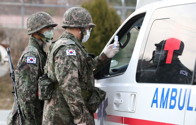 South Korean soldiers wearing masks to prevent contacting the coronavirus stand guard at a checkpoint of a military base in Daegu