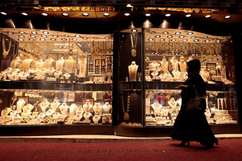 FILE PHOTO: A woman walks past gold jewellery displayed in a shop window at the Gold Souq in Dubai