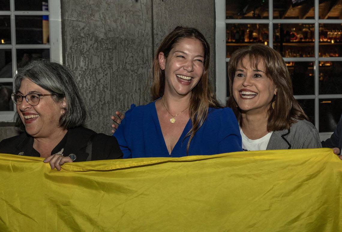 Sabina Covo, center, the winner of the District 2 special election in the city of Miami, poses with a Colombian flag as she celebrates along with Miami-Dade County Mayor Daniella Levine Cava , left and Annette Taddeo, right, during a party at The Taurus in Coconut Grove, February 27, 2023.