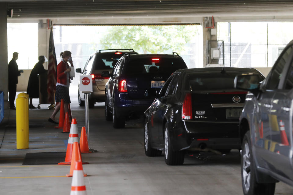 In this June 26, 2020 photo, cars line up during a drive-thru naturalization service in a parking structure at the U.S. Citizenship and Immigration Services headquarters on Detroit's east side. The ceremony is a way to continue working as the federal courthouse is shut down due to Coronavirus. The U.S. has resumed swearing in new citizens but the oath ceremonies aren't the same because of COVID-19 and a budget crisis at the citizenship agency threatens to stall them again. (AP Photo/Carlos Osorio)