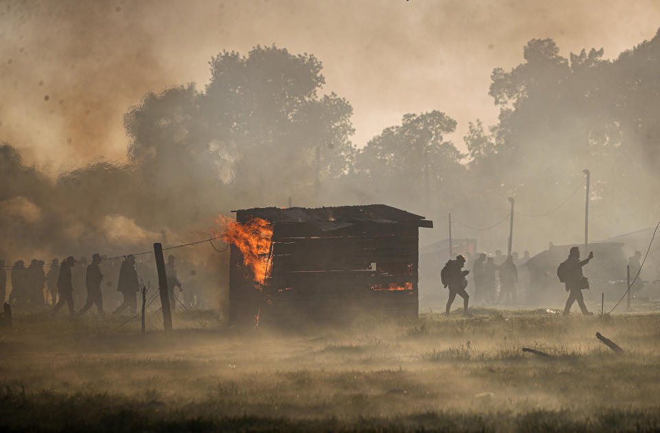 Police carry out an eviction at a squatters camp where a shack home burns in Guernica, Buenos Aires province, Argentina, Thursday, Oct. 29, 2020. A court ordered the eviction of families who are squatting here since July, but the families say they have nowhere to go amid the COVID-19 pandemic. (AP Photo/Natacha Pisarenko)