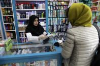 A pharmacist shows gloves to a customer in a pharmacy in downtown Tehran, Iran, Thursday, Feb. 27, 2020. Amid fear and uncertainty caused by the spread of a new virus, Iranians are taking extra caution to avoid getting infected, as authorities canceled Friday prayers in Tehran, Qom and other cities. (AP Photo/Vahid Salemi)