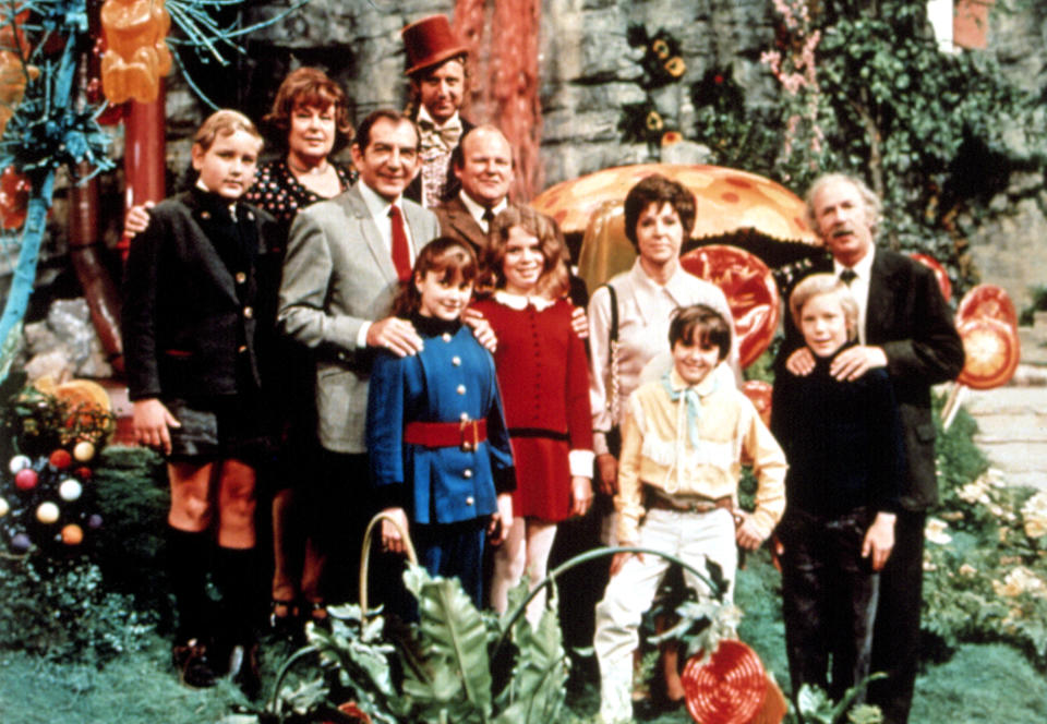 The cast of Willy Wonka stands in a garden