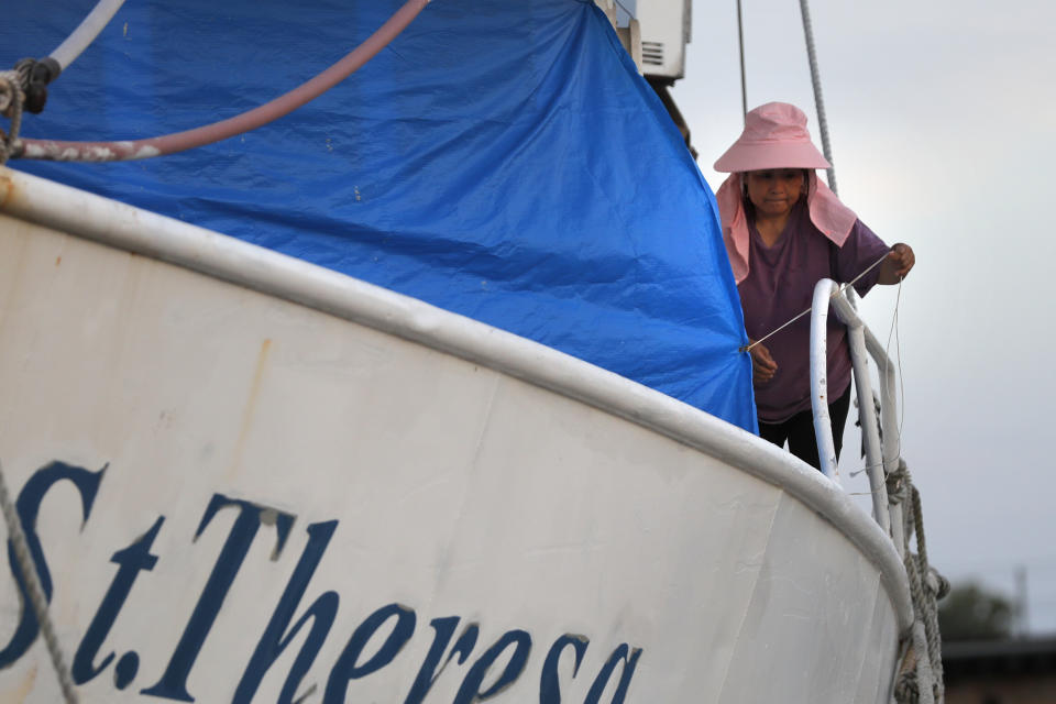 Tuyet Tran ties down a tarp on her shrimp boat in Morgan City, La. Monday, May 11, 2020. Attempts to curb the spread of COVID-19 have visited a kind of triple economic whammy on the state. As oil prices have plummeted, the industry laid off workers. Tourism has dried up, meaning more lost jobs. And one major tourist draw — cuisine built around fin fish, shrimp, oyster and crabs — is also suffering. (AP Photo/Gerald Herbert)