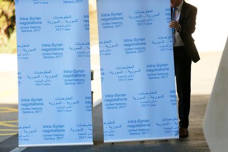 A member of UN staff installs a roll-up sign before the beginning of the Geneva IV conference on Syria at the United Nations office in Geneva, Switzerland, February 23, 2017. REUTERS/Pierre Albouy