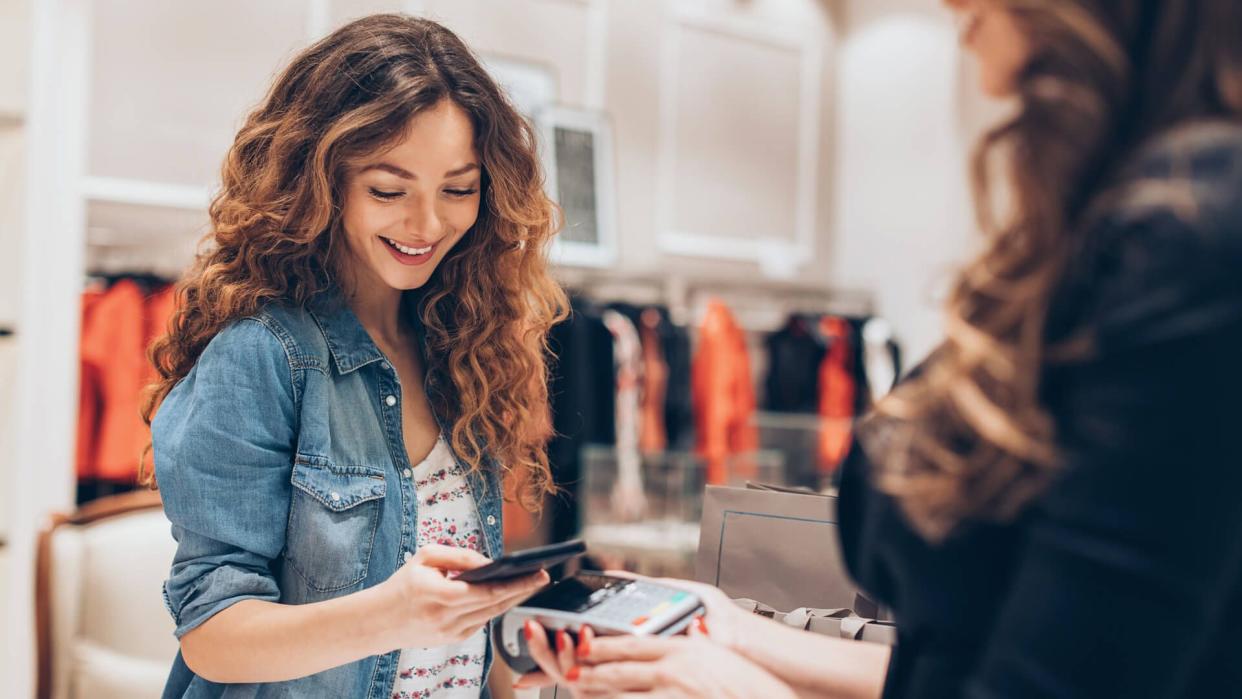 Young woman making a contactless payment in a fashion store.