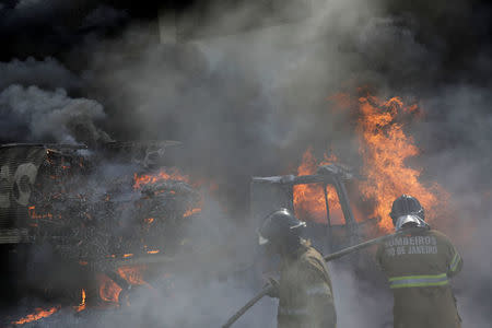 Firefighters try to extinguish a fire on a truck burned during violent clashes between rival gangs at a street near Brasil avenue near Cidade Alta slum in Rio de Janeiro, Brazil, May 2, 2017. REUTERS/Ricardo Moraes