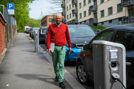 Bjart Holtsmark, an analyst at Statistics Norway, is shown here walking past electric cars being charged on an Oslo street