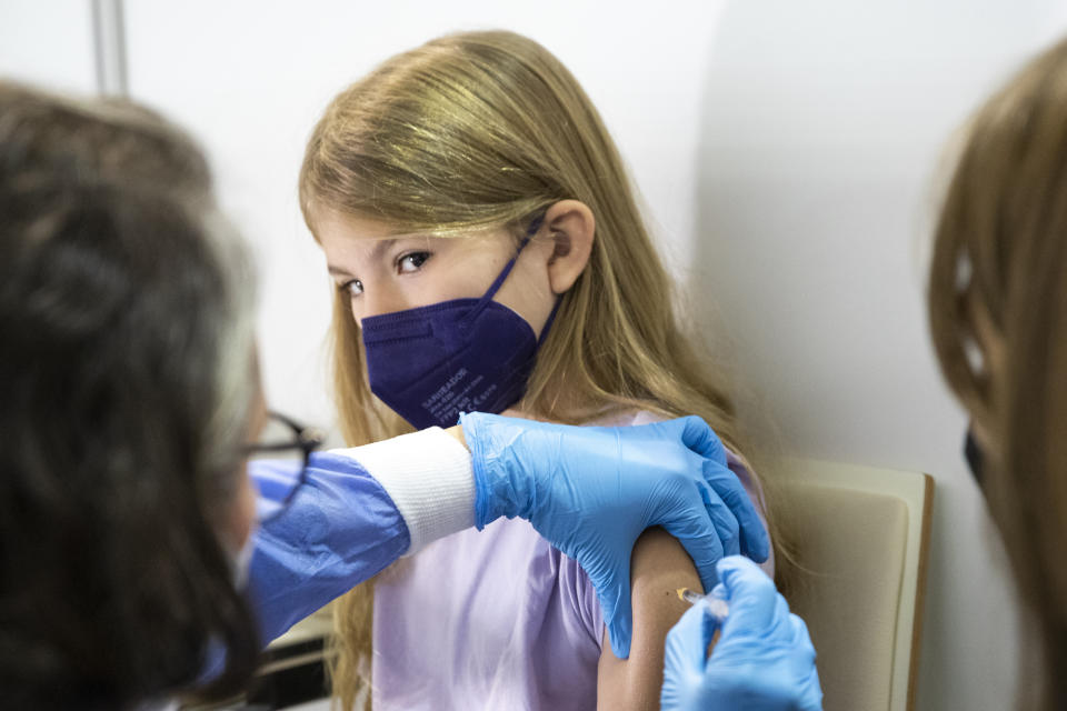 FILE - A young patient receives the Pfizer vaccine against COVID-19 in Vienna, Austria, Monday, Nov. 15, 2021. This was supposed to be the Christmas in Europe where family and friends could once again embrace holiday festivities and one another. Instead, the continent is the global epicenter of the COVID-19 pandemic as cases soar to record levels in many countries. With infections spiking again despite nearly two years of restrictions, the health crisis increasingly is pitting citizen against citizen — the vaccinated against the unvaccinated.(AP Photo/Lisa Leutner, File)