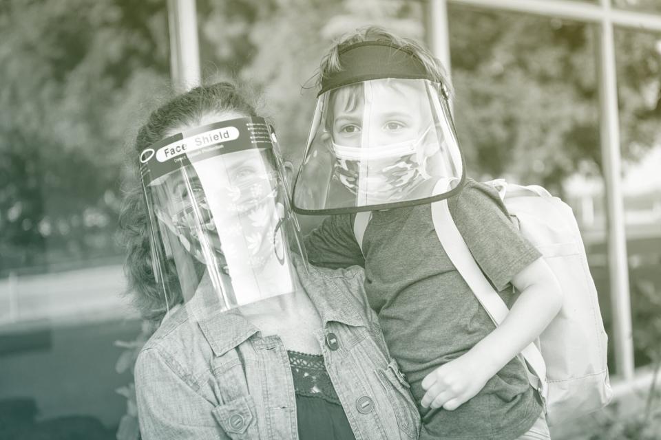 Mother and son ready to go back to school wearing protective face masks and face shields
