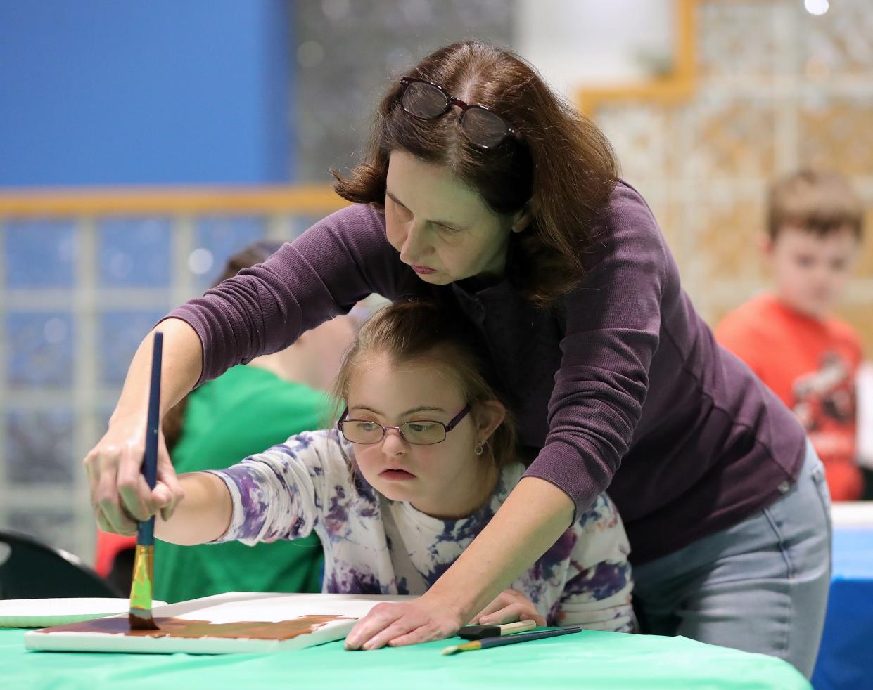 Laura Gehlmann, top, and her daughter Elaina, 13, of Medina work on a holiday painting during an Integrated Community Solutions art class at Medina County Board of Developmental Disabilities in Medina.