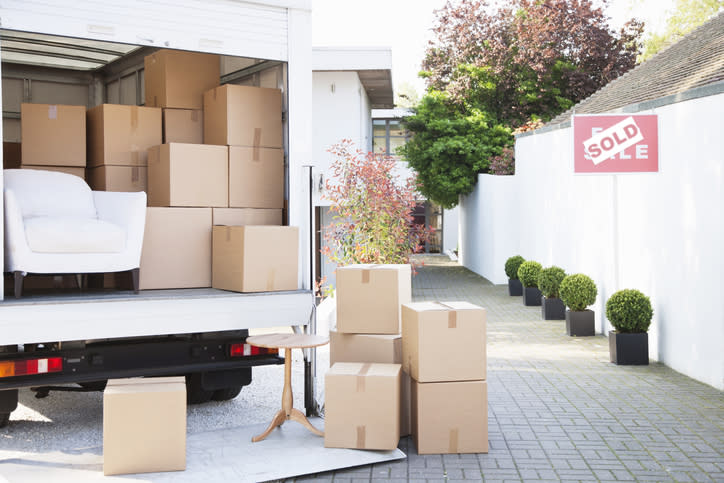 Pictured are boxes on the ground next to a packed moving van. 