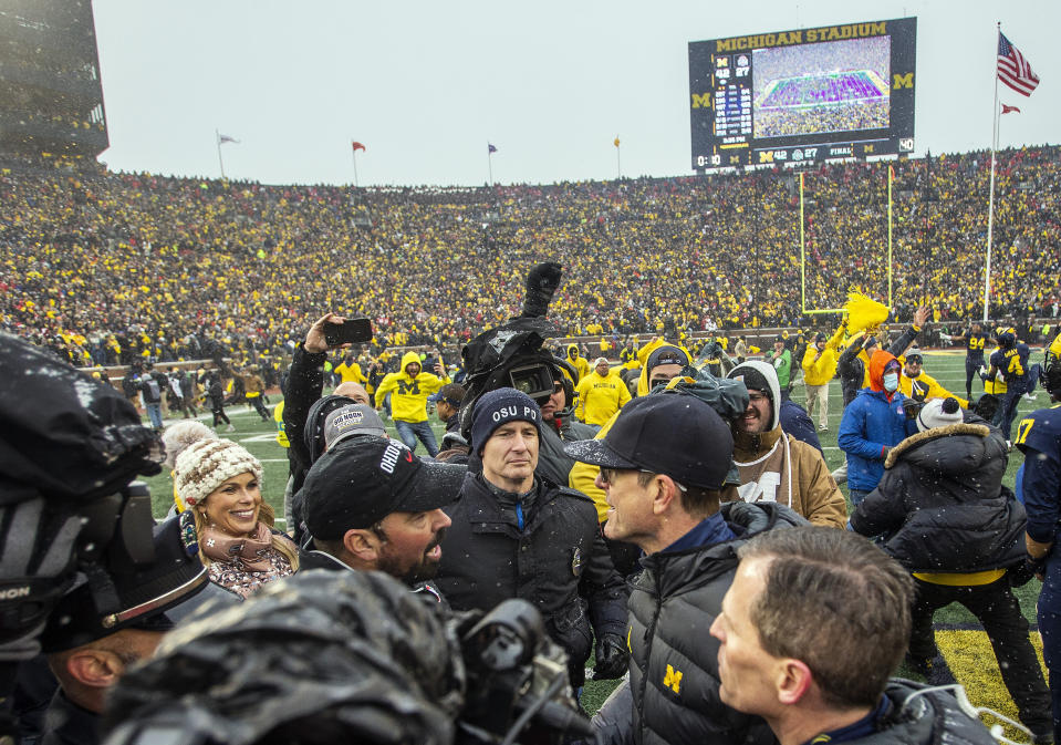 FILE - Ohio State head coach Ryan Day, center left, shakes hands with Michigan head coach Jim Harbaugh, center right, after an NCAA college football game in Ann Arbor, Mich., Saturday, Nov. 27, 2021. The final game of Harbaugh's suspension will be served Saturday, Nov. 25, 2023, keeping the former Michigan quarterback, who finally flipped the rivalry after a decade and a half of dominance by the Buckeyes, off the sideline as his team tries to make it three straight against Ohio State. (AP Photo/Tony Ding, File)