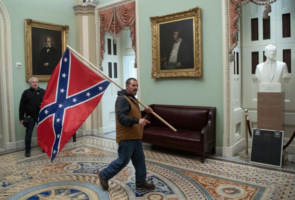 A supporter of President Donald Trump carries a Confederate flag as he protests in the U.S. Capitol Rotunda on Jan. 6, 2021. Demonstrators breeched security and entered the Capitol as Congress debated the a 2020 presidential election Electoral Vote Certification. (Saul Loeb/AFP via Getty Images)