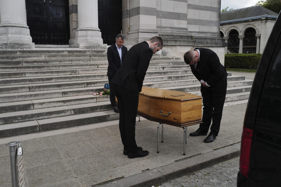 Paris undertaker Franck Vasseur, rear left, and pallbearers, Louis Mercier, and Allan Pottier, right, pay their respects during a funeral ceremony at Pere Lachaise cemetery in Paris, Friday, April 24, 2020. As body after body has passed through his rubber-gloved hands, sealed in double-layered bags for disposal, Paris undertaker Franck Vasseur has become increasingly concerned about the future after the coronavirus pandemic. (AP Photo/Francois Mori)
