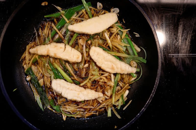 A dish containing pieces of 3D-printed cultivated grouper fish is prepared for a tasting at the offices of Steakholder Foods in Rehovot