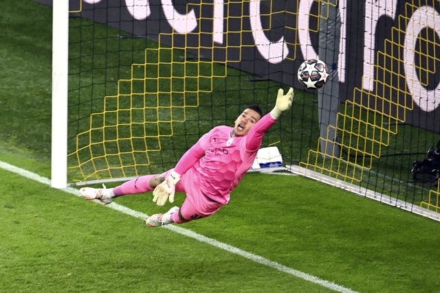 Manchester City goalkeeper Ederson dives to save a shot 