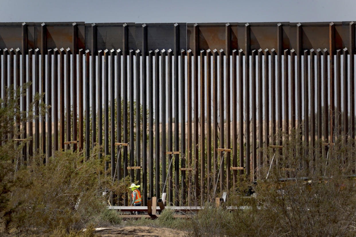 A government contractor walks beside a completed section of Pentagon-funded border wall along the Colorado River this month in Yuma, Ariz.&nbsp; (Photo: ASSOCIATED PRESS)