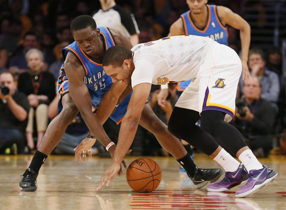 Oklahoma City Thunder point guard Reggie Jackson, left, and Los Angeles Lakers small forward Xavier Henry reach for a loose ball during the first half of an NBA basketball game in Los Angeles, Sunday, March 9, 2014. (AP Photo/Danny Moloshok)