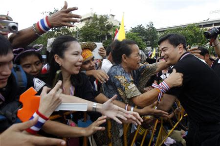 Anti-government protesters greet former Prime Minister Abhisit Vejjajiva (R) as he joins them during a rally against the government-backed amnesty bill at the Democracy monument in central Bangkok November 24, 2013. REUTERS/Chaiwat Subprasom