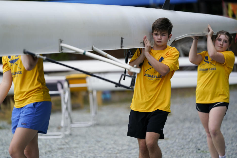 Callum Bradford, center, and his team, carry their boat to the ramp as they get ready for a rowing club practice at Jordan Lake, Friday, Oct. 6, 2023, in Apex, N.C. Bradford, a transgender teen from Chapel Hill needed mental health care after overdosing on prescription drugs. He was about to be transferred to another hospital due to a significant bed shortage. A North Carolina hospital network is referring transgender psychiatric patients to treatment facilities that do not align with their gender identities. Though UNC Hospitals policy discourages the practice, administrators say a massive bed shortage is forcing them to make tough decisions. (AP Photo/Erik Verduzco)