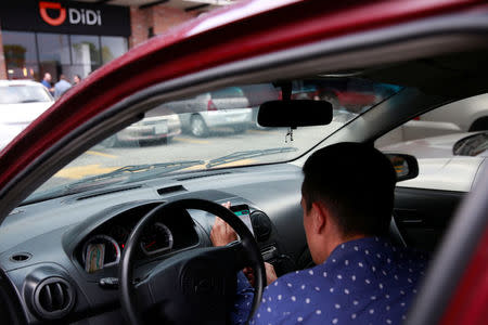A new DIDI driver set up his mobile phone inside a car outside the new drivers center of the Chinese ride-hailing firm in Toluca, Mexico, April 23, 2018. REUTERS/Carlos Jasso