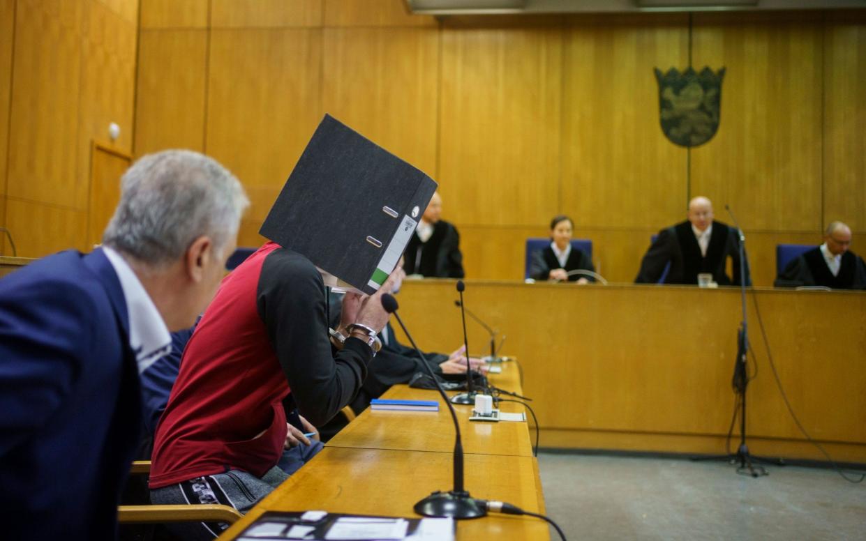 With a file folder in front of his face, the Iraqi Taha Al-J. (2nd from left) takes his seat in the dock before the verdict is handed down in the Frankfurt Higher Regional Court in Frankfurt, Germany, Tuesday, Nov, 30, 2021. The Federal Prosecution accuses him of genocide, crimes against humanity, war crimes, human trafficking and murder. As a suspected member of the terrorist militia IS, he is alleged to have held a Yazidi woman and her daughter as slaves and abused them. In the process, he allegedly tied up the five-year-old in Fallujah, Iraq, where the child died of thirst in agony, according to the indictment. (Frank Rumpenhorst/Pool via AP) - Frank Rumpenhorst /dpa-Pool 