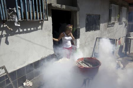 A woman covers his mouth and nose during a fumigation campaign at the Petare slum to help control the spread of the mosquito-borne Zika virus in Caracas, February 3, 2016. REUTERS/Marco Bello