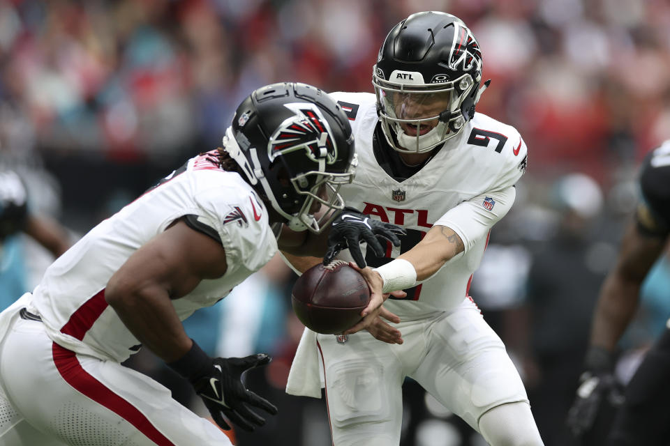 Atlanta Falcons quarterback Desmond Ridder (9), right, hands-off the ball during an NFL football game between the Atlanta Falcons and the Jacksonville Jaguars at Wembley stadium in London, Sunday, Oct. 1, 2023. (AP Photo/Ian Walton)