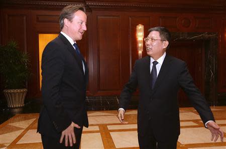 Shanghai Mayor Yang Xiong directs British Prime Minister David Cameron (L) to the meeting venue in Shanghai December 3, 2013. REUTERS/Eugene Hoshiko/Pool